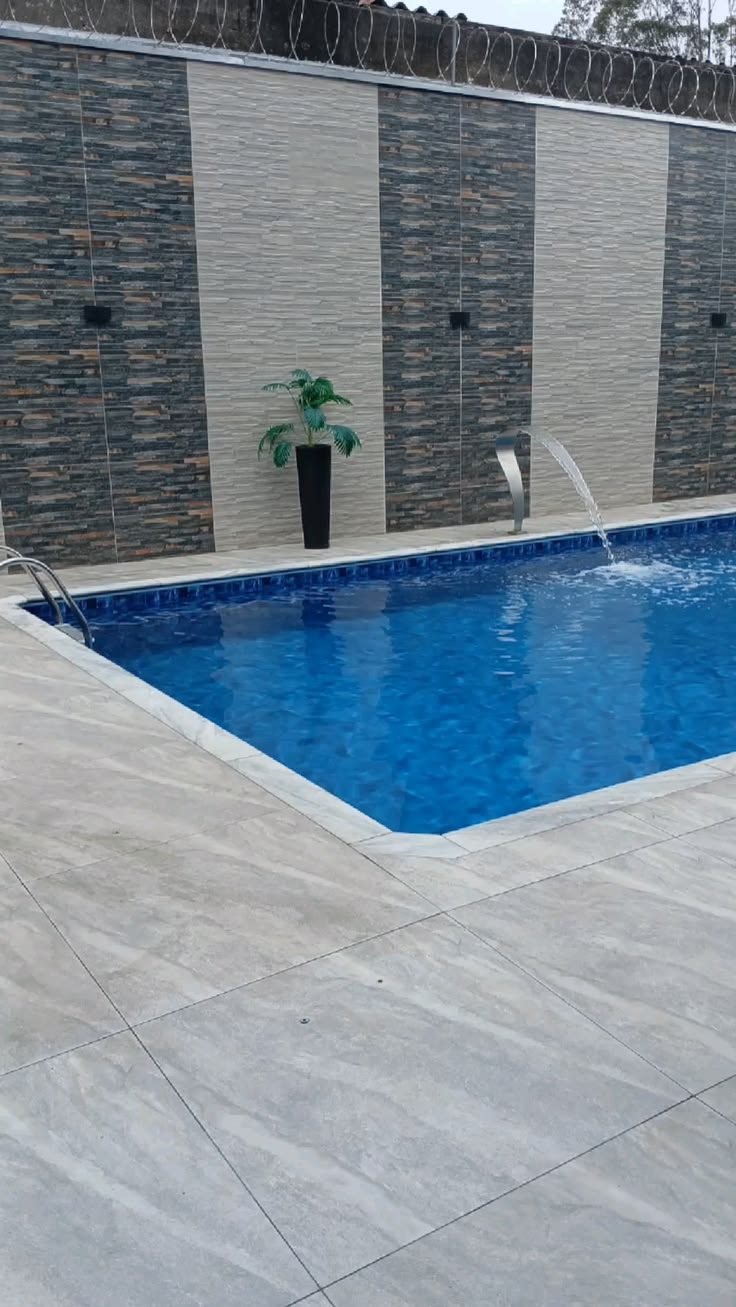 Piscina de alvenaria com cascata e borda em porcelanato, construída pela WF Construção